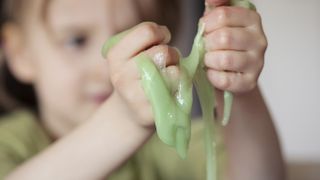 Check out our roundup of the best slime kit deals. Here, a child plays with slime with their hands.