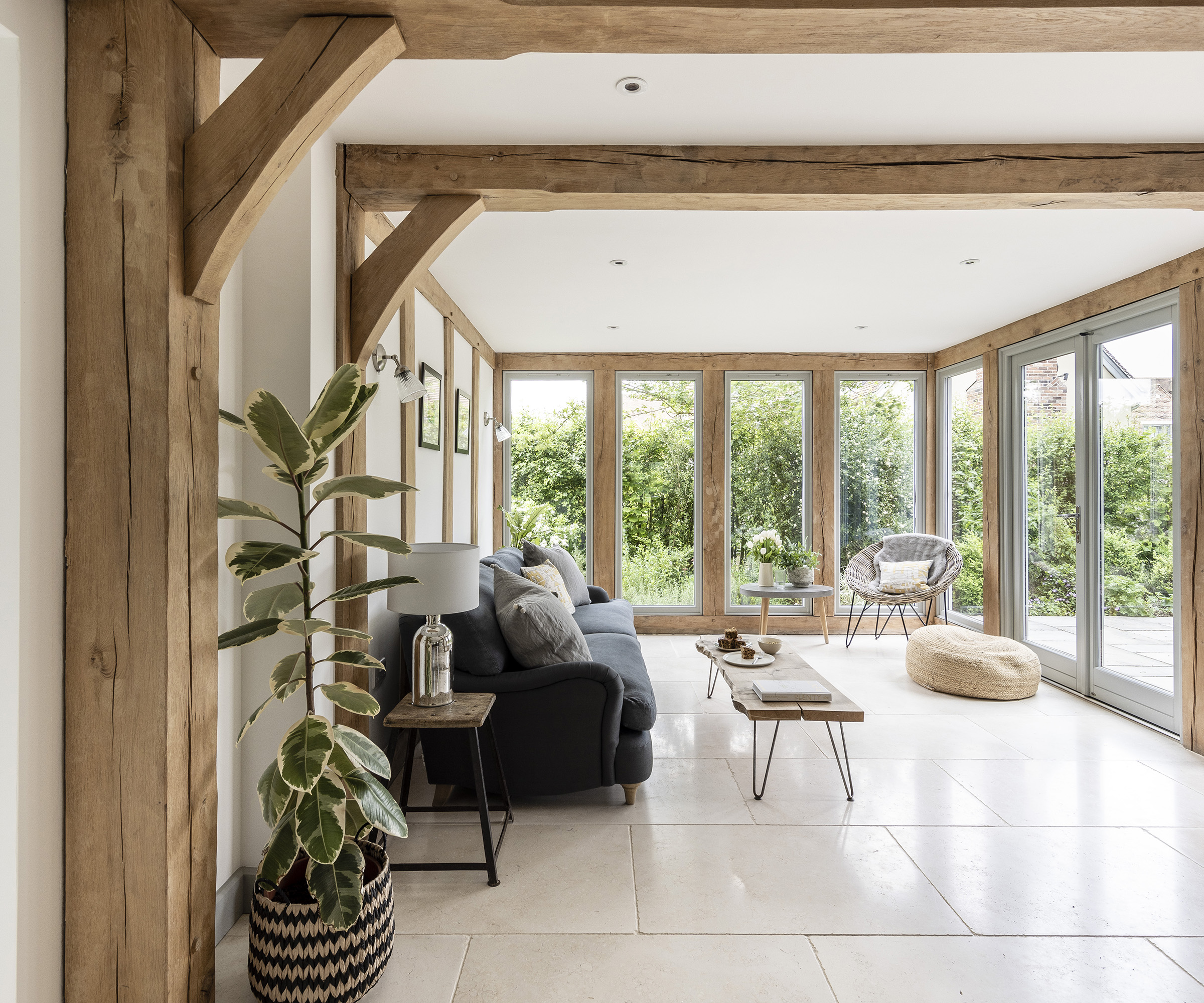 An open living room in an oak frame home with exposed beams and tiled floor