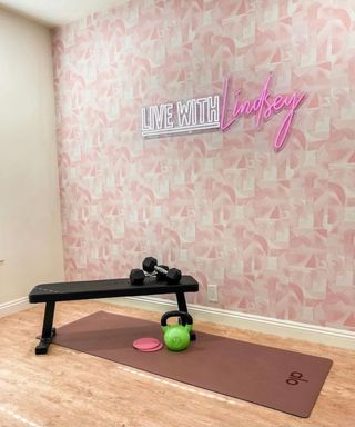 Basement gym idea with wallpaper feature wall signage weight bench and yoga mat