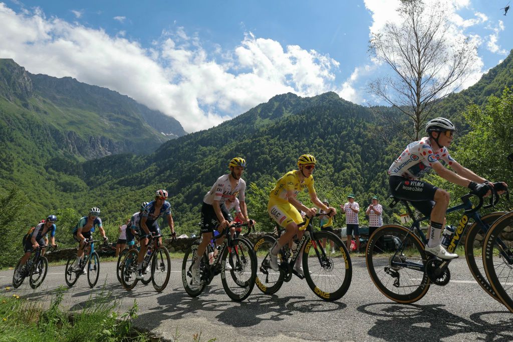 Team Visma - Lease a Bike team's Danish rider Jonas Vingegaard wearing the climber's polka dot (dotted) jersey (second placed in the category) (R) and UAE Team Emirates team's Slovenian rider Tadej Pogacar wearing the overall leader's yellow jersey cycle with the pack of riders (peloton) in the ascent of the Col de d'Agnes during the 15th stage of the 111th edition of the Tour de France cycling race, 197,7 km between Loudenvielle and Plateau de Beille, in the Pyrenees mountains, southwestern France, on July 14, 2024. (Photo by Thomas SAMSON / AFP)