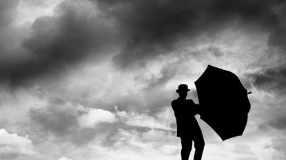 A man holds an umbrella on a cloudy day.