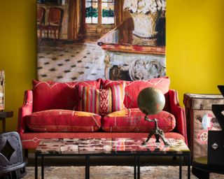 red sofa in room with bright yellow wall and large artwork
