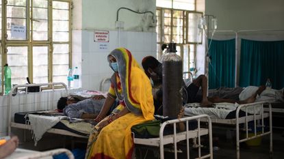 A relative sits with her family member in a hospital in Rajasthan, India