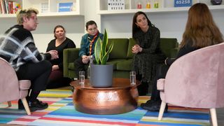 Kate Middleton sits on a sofa with other people during her visit to Shout in 2022