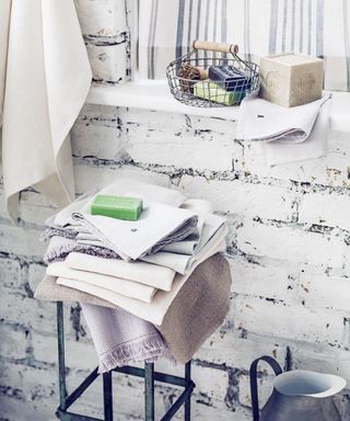 White painted brick wall, stool with stack of linen napkins