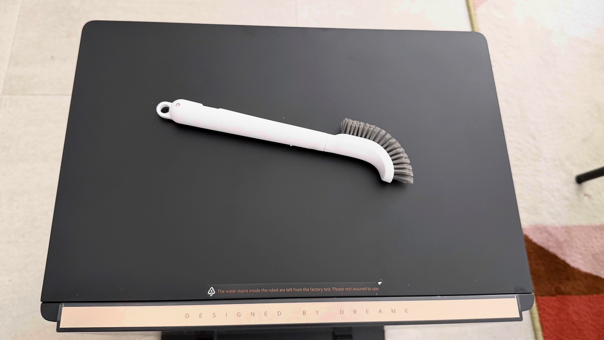 A long-handled brush on top of the Dreame Aqua10 Ultra dock