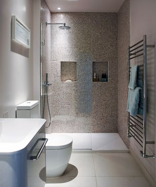 Alcove shelving shower design for a small bathroom in gray mosaic tiles.