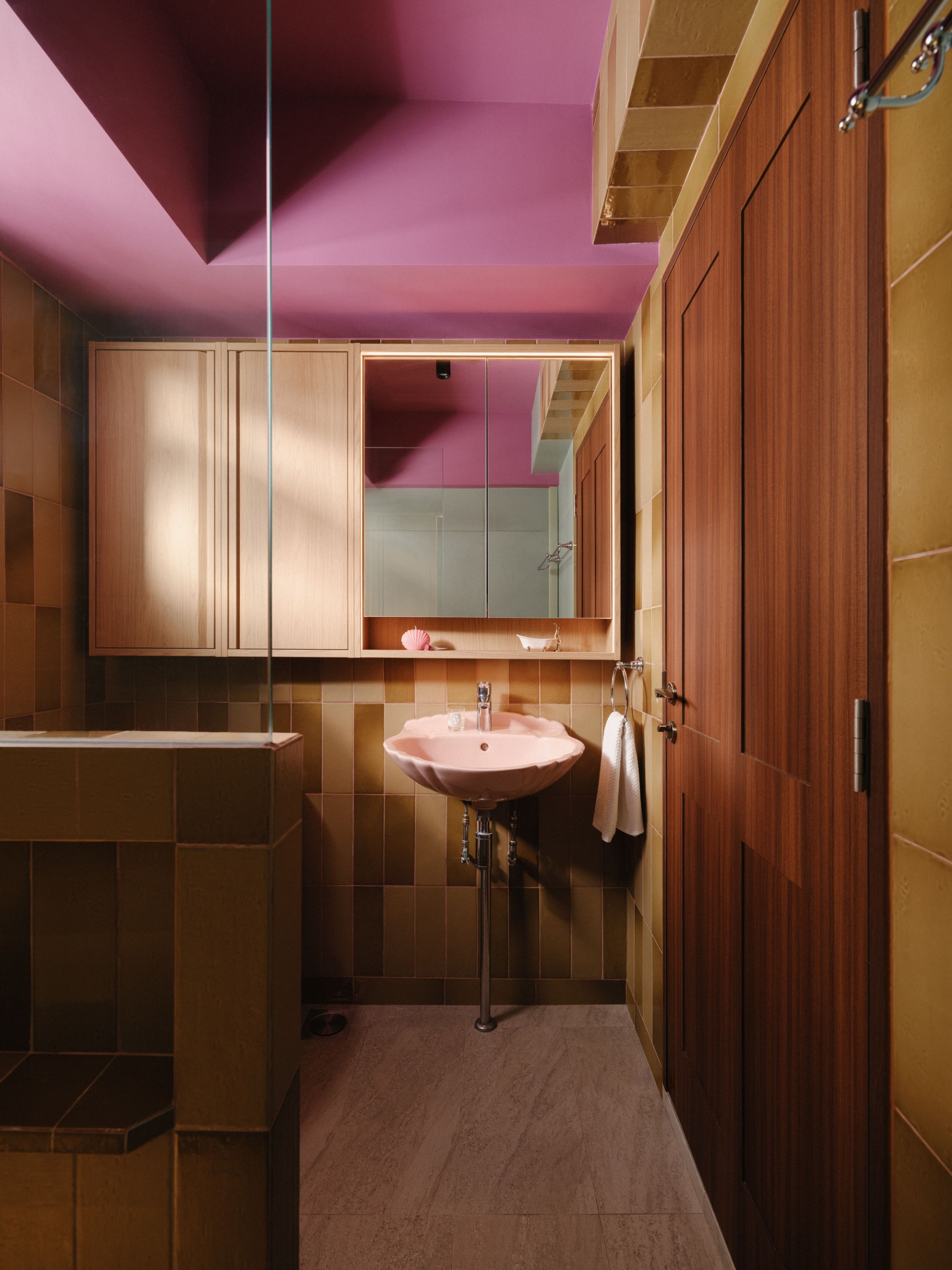a pink and terracotta bathroom with rectangular wall tiles and a pink shell sink
