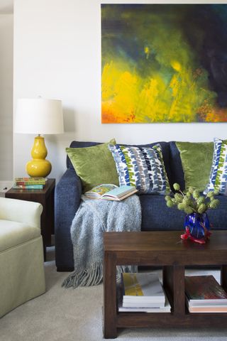 Living room with canary yellow lamp with similar tones reflected in artwork on wall and house plant on coffee table