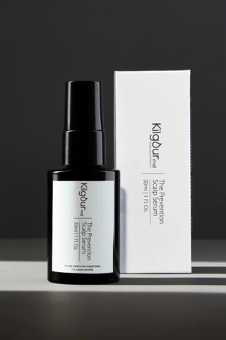 Kilgour MD scalp serum bottle and box on a table with a gray wall in the background