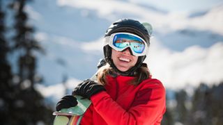 Woman wearing ski goggles and carrying skis