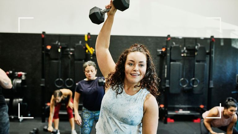 Woman lifting dumbbell above her head in the gym after learning about the top workout mistakes