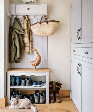 A mudroom with shoe storage in a bench, an overhead cupboard and full wall grey cabinets