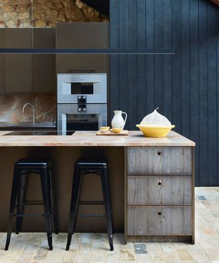 Modern kitchen with blue cabinetry, dark wood and marble island, stool seating