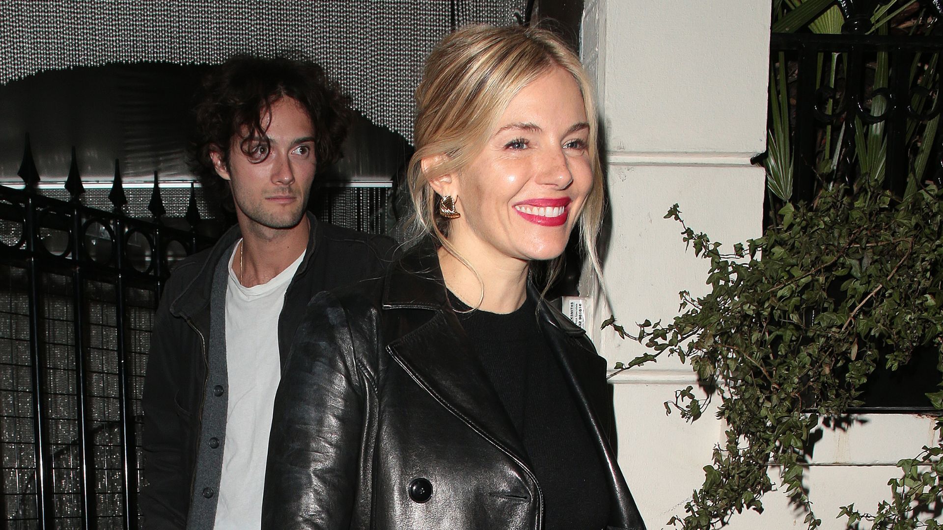 Sienna Miller exits a restaurant wearing Missoma waves earrings with a leather trench coat.