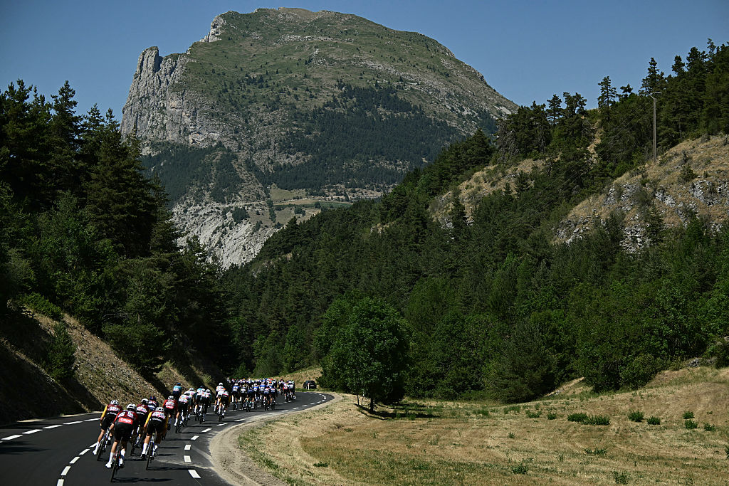 The pack of riders (peloton) cycles during the 19th stage of the 113th edition of the Tour de France cycling race, 127,9 km between Gap and Alpe d'Huez in the French Alps, on July 24, 2026. (Photo by Loic VENANCE / AFP)