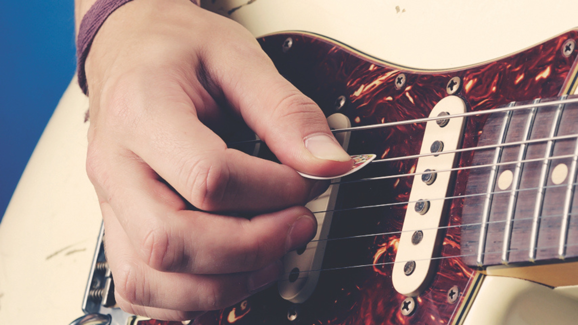 A man plays electric guitar with a guitar pick
