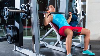 Woman performing incline bench press using a Smith machine