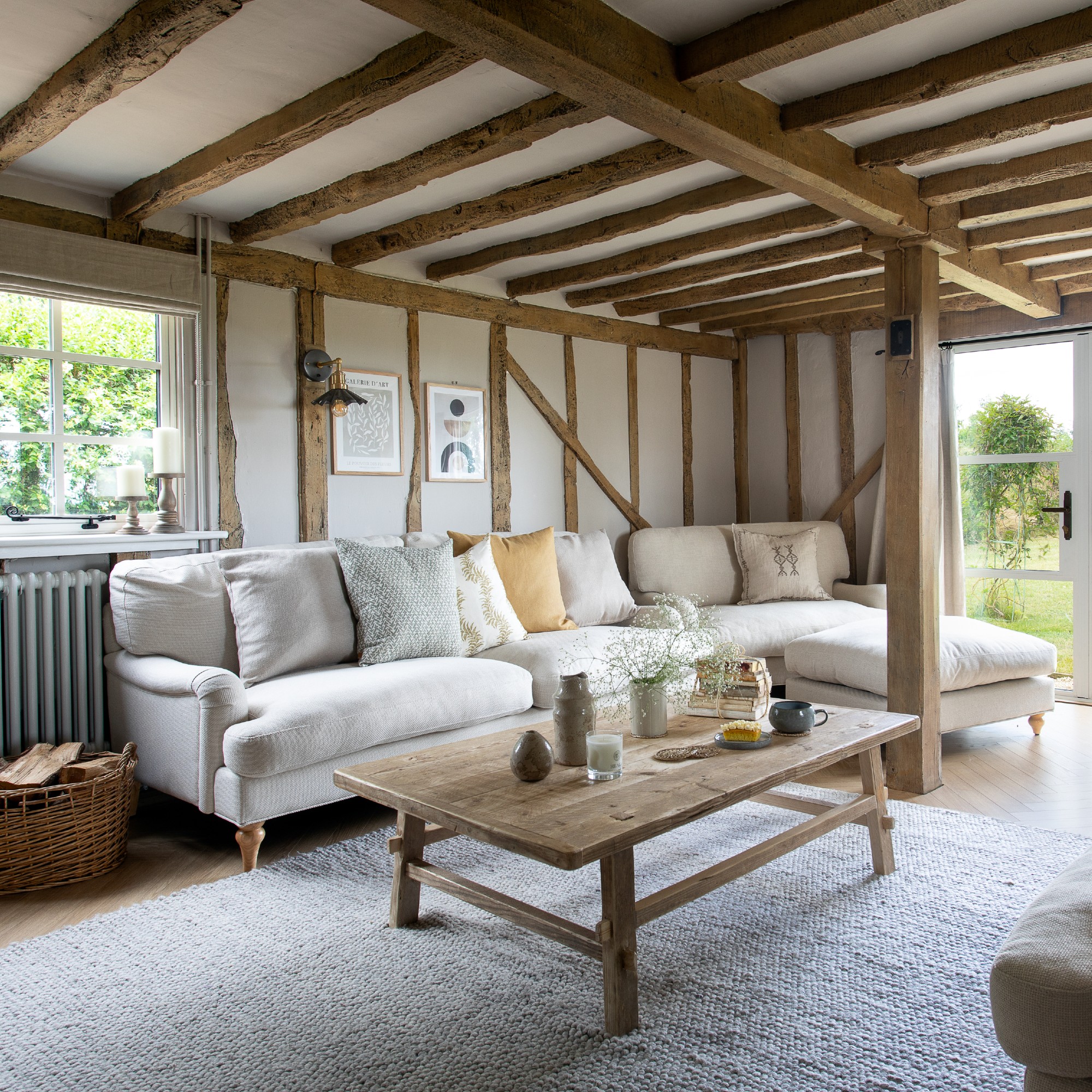 A neutral rustic living room with exposed beams, vintage-style coffee table and a cream sofa
