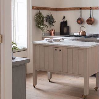 cream kitchen with island with wheels in kitchen with wooden floor