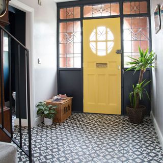 Fashionable hallway with a yellow painted door , plant décor and a woven storage basket