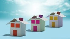 Three paper houses in a row against a blue sky background.