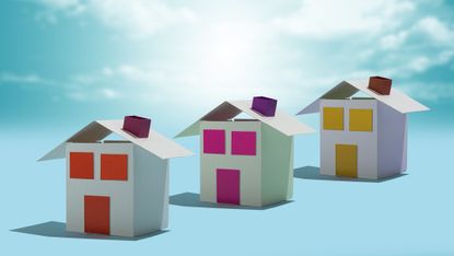 Three paper houses in a row against a blue sky background.