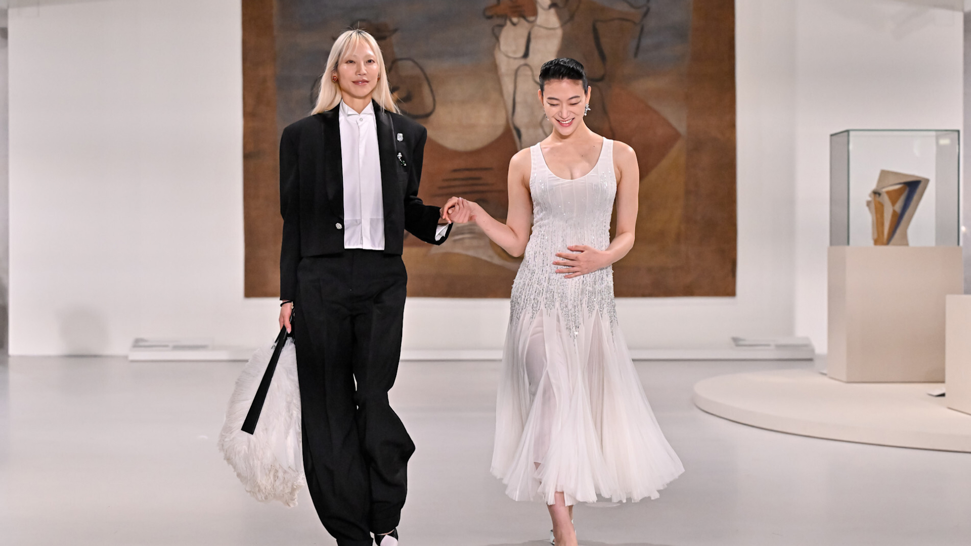 a pregnant model walks with another model on the Chanel Metiers d'Art runway in Korea
