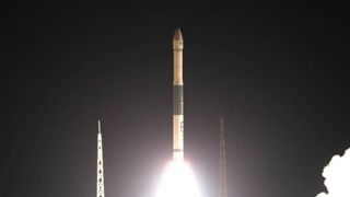 a white rocket launches into a dark night sky.