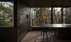 dark wood clad minimalist living space with large window inside Oslo house Villa Nikkesmelle by Gartnerfuglen