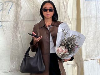 stylish fashion influencer holding flowers wearing a brown leather jacket and sunglasses