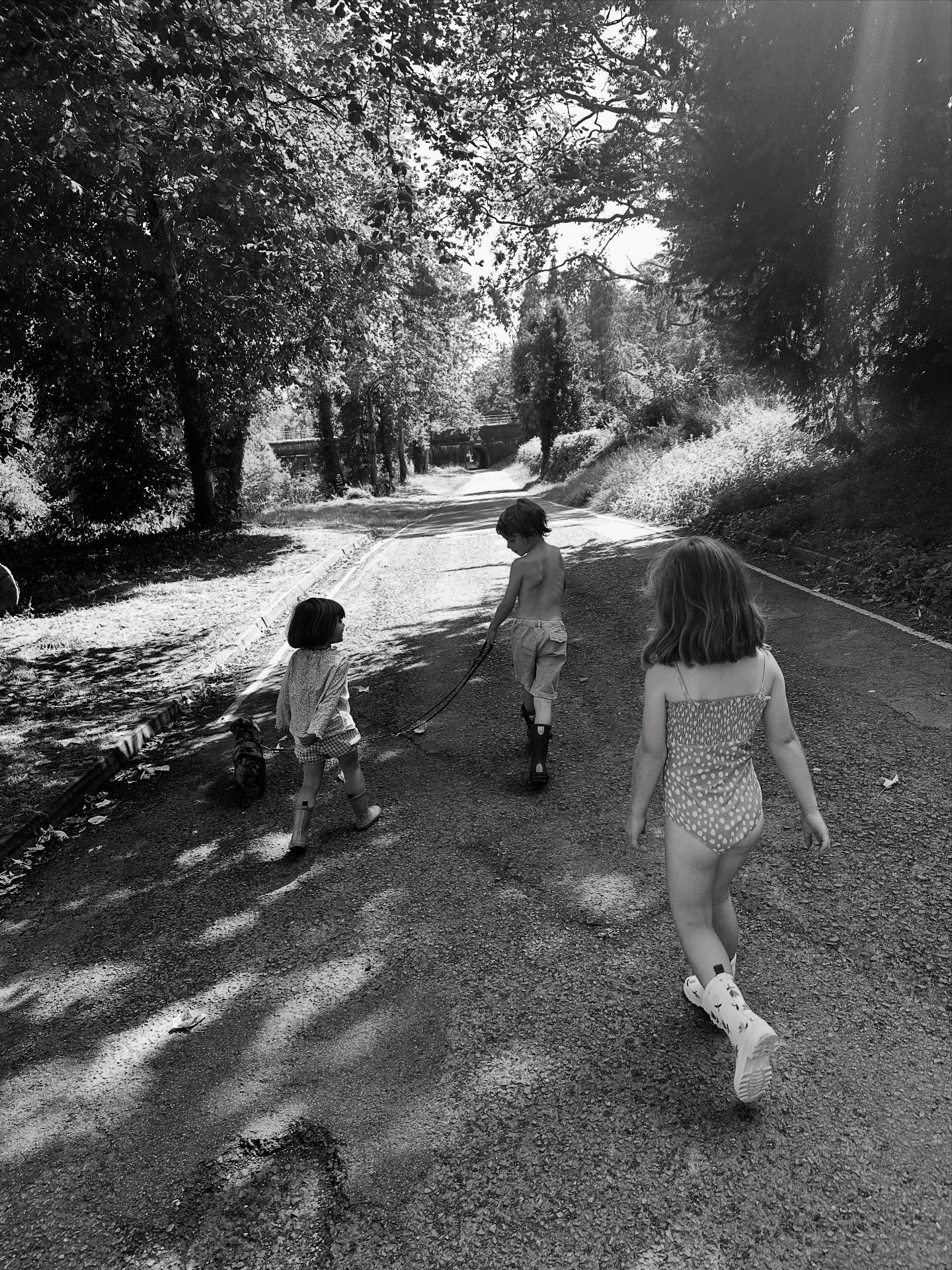 Three children in swimwear marching down a country lane