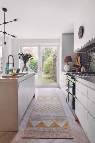 A white kitchen with wooden floor and a soft woven patterned rug