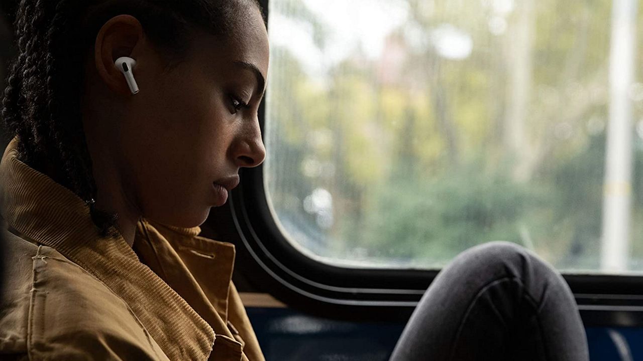 Woman sitting in train carriage wearing Apple AirPods