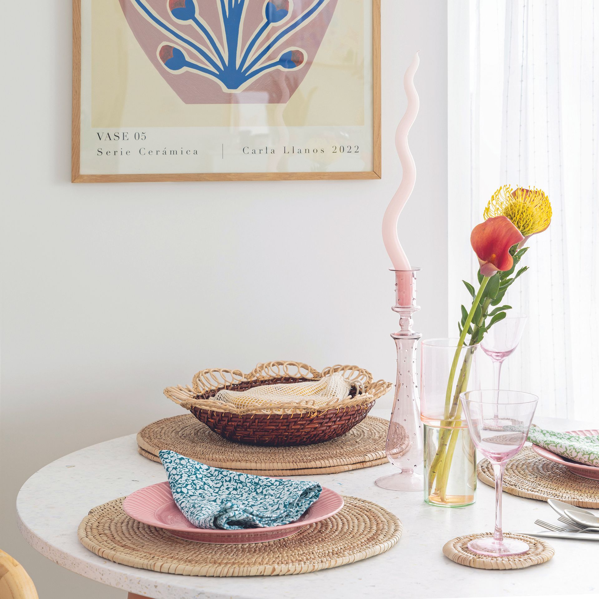 Kitchen dining table in white with rattan placemats and crockery.