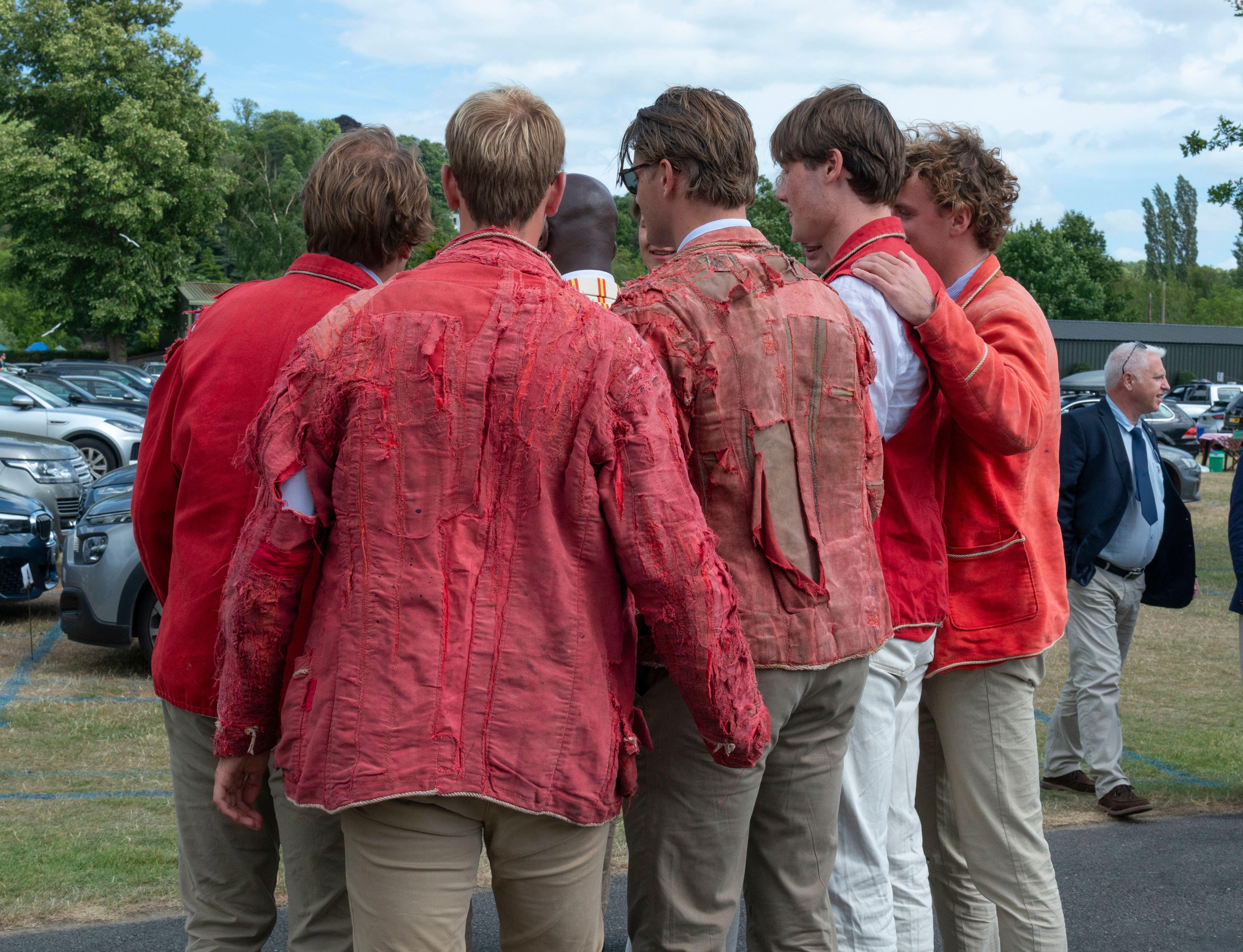Competitors huddle for a selfie after winning the most prestigious and oldest student rowing event of The Netherlands. they wear read blazers, which are in tatters.