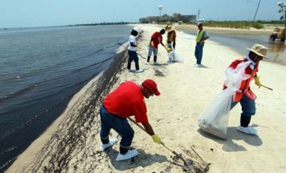 Workers cleanup oil left on the beaches of Waveland, Mississippi.