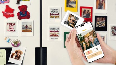 The VidaBay Snap with a smartphone updating the photos on the small e-ink screen with several more e-ink magnets int he background