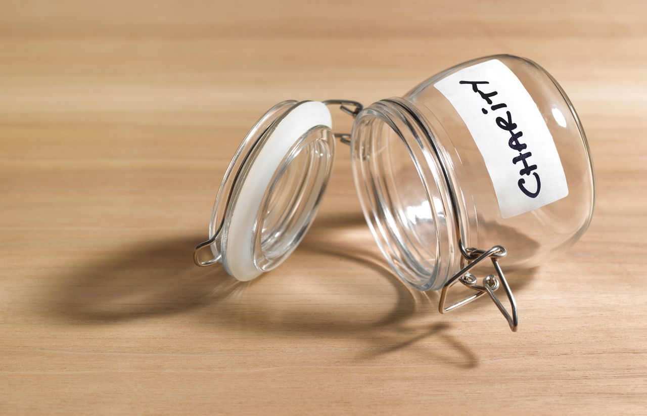 open empty glass jar with &quot;charity&quot; label against woodgrain background