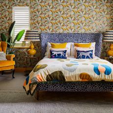 A bedroom with yellow floral wallpaper and a leopard-print bed frame