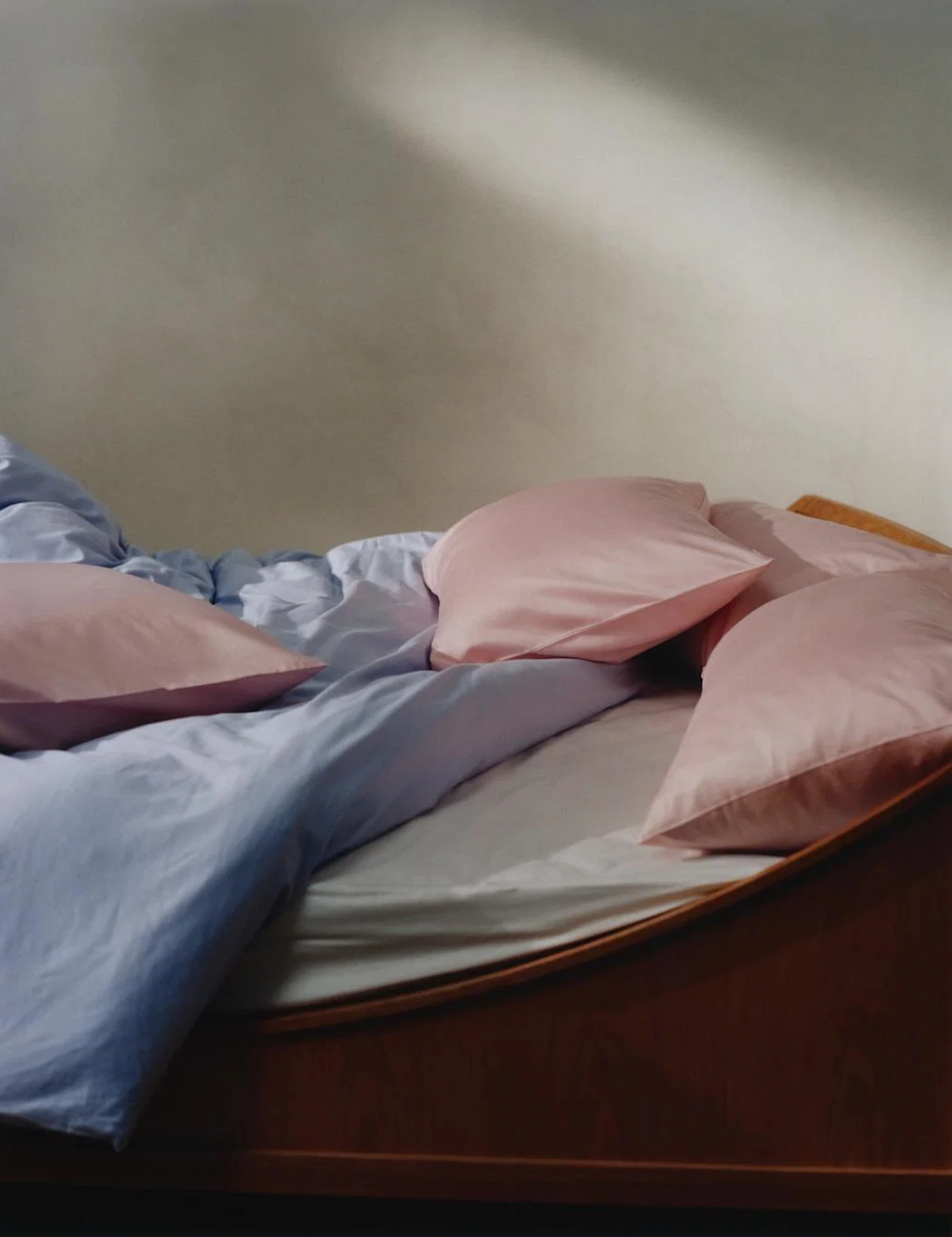 Ice blue duvet styled with rosy pink pillowcases and a cloud white fitted sheet inside of a minimalist bedroom