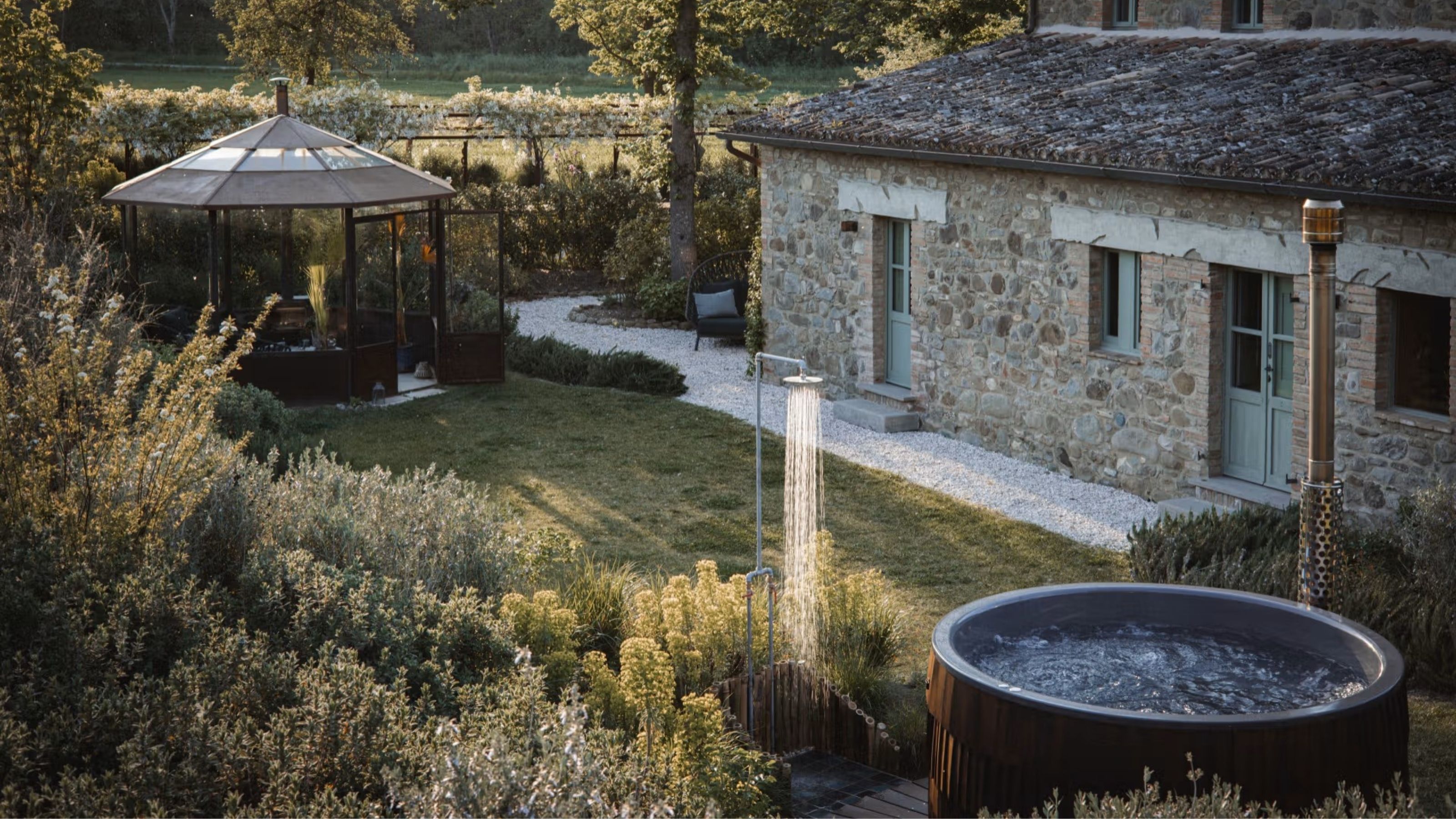 A sun-lit shot of a monastery, now converted into a texturally decorated hotel, with original stone walls preserved alongside greenery and sculptural design accents.