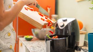 picture of woman emptying cut veggies into air fryer