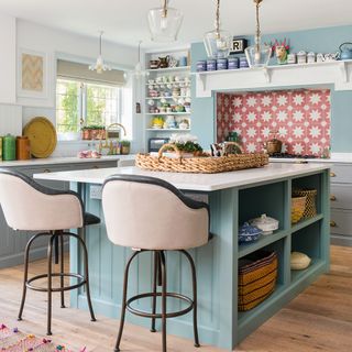 light blue kitchen with island, bar seats and pink patterned tile splashback