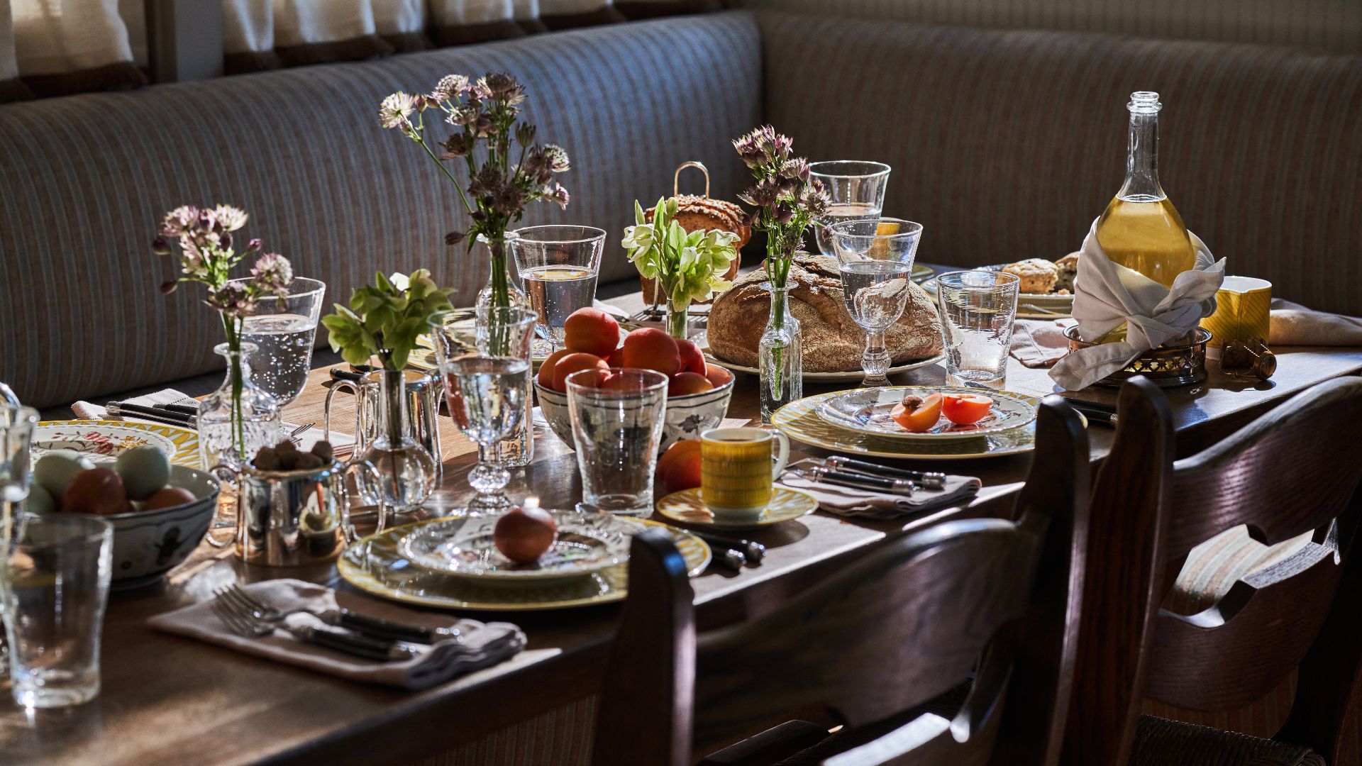Breakfast table set with bud vases of flowers, bowls of eggs and a bottle of juice