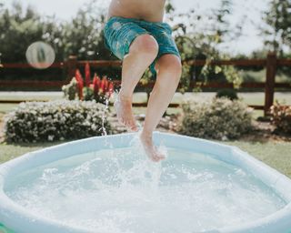 A boy jumping up in a paddling pool
