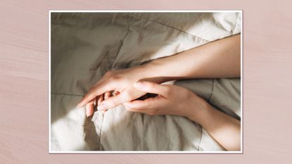 Image of two hands on a blanket, in a white frame against a dusky pink watercolour-style backround