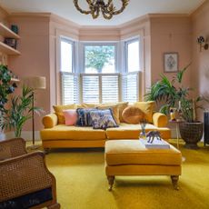 Pink living room with yellow carpet, sofa and ottoman