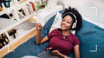 Woman lying down on bed surrounded by books with headphones on and eyes closed, listening to the best podcasts for mental health