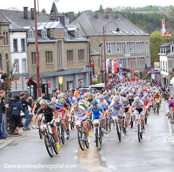 A large pack of riders makes its way through the streets of Houffalize.